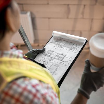 high-angle-female-construction-worker-holding-coffee-blueprint